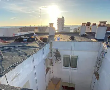 Operario con cuerdas trabajando en la pared interior de un edificio al atardecer